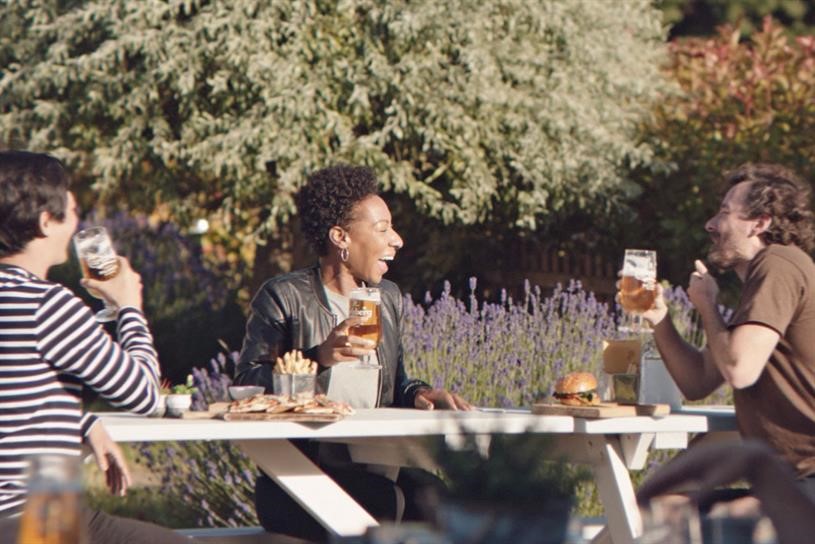 Ad for Carlsberg beer with friends at an outdoor pub social distancing